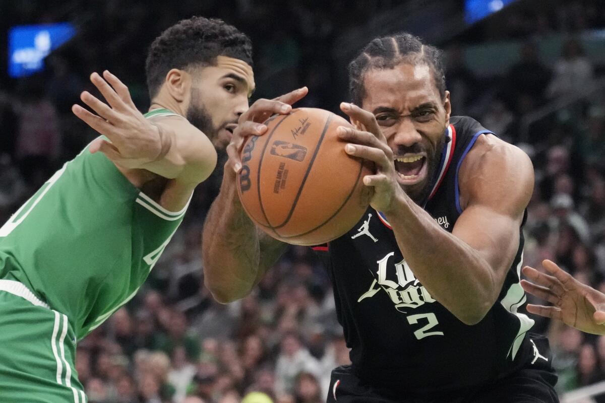 Clippers forward Kawhi Leonard hangs onto the ball after driving past Boston Celtics forward Jayson Tatum.