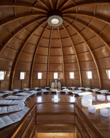 The interior of a wooden dome, with white mats laid out in a semicircle on the floor