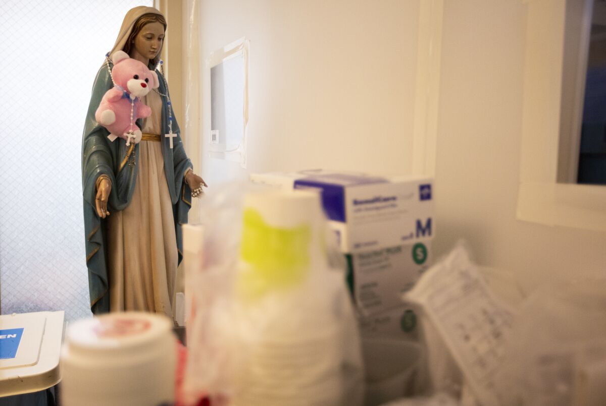 A small statue of the Virgin Mary is seen standing amid medical supplies in a hospital room