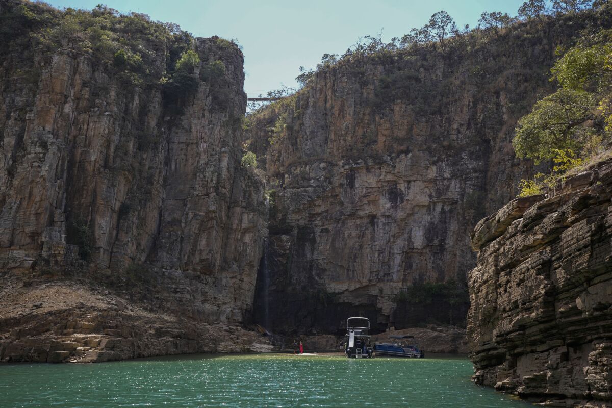 A tourist boat navigates through a canyon in Furnas Lake, near Capitolio City, Brazil, Sept. 2, 2021. A massive slab of rock broke away on Saturday, Jan. 8, 2022, from the canyon wall and and toppled onto pleasure boaters killing at least two people and injuring dozens at the popular tourist destination in Minas Gerais state. (AP Photo/Andre Penner)