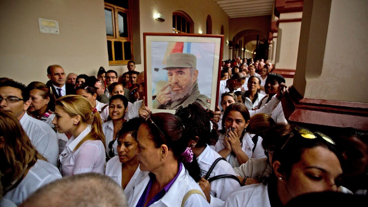Cuban doctors working in Venezuela hold a photo of Fidel Castro during a tribute after his death in November.