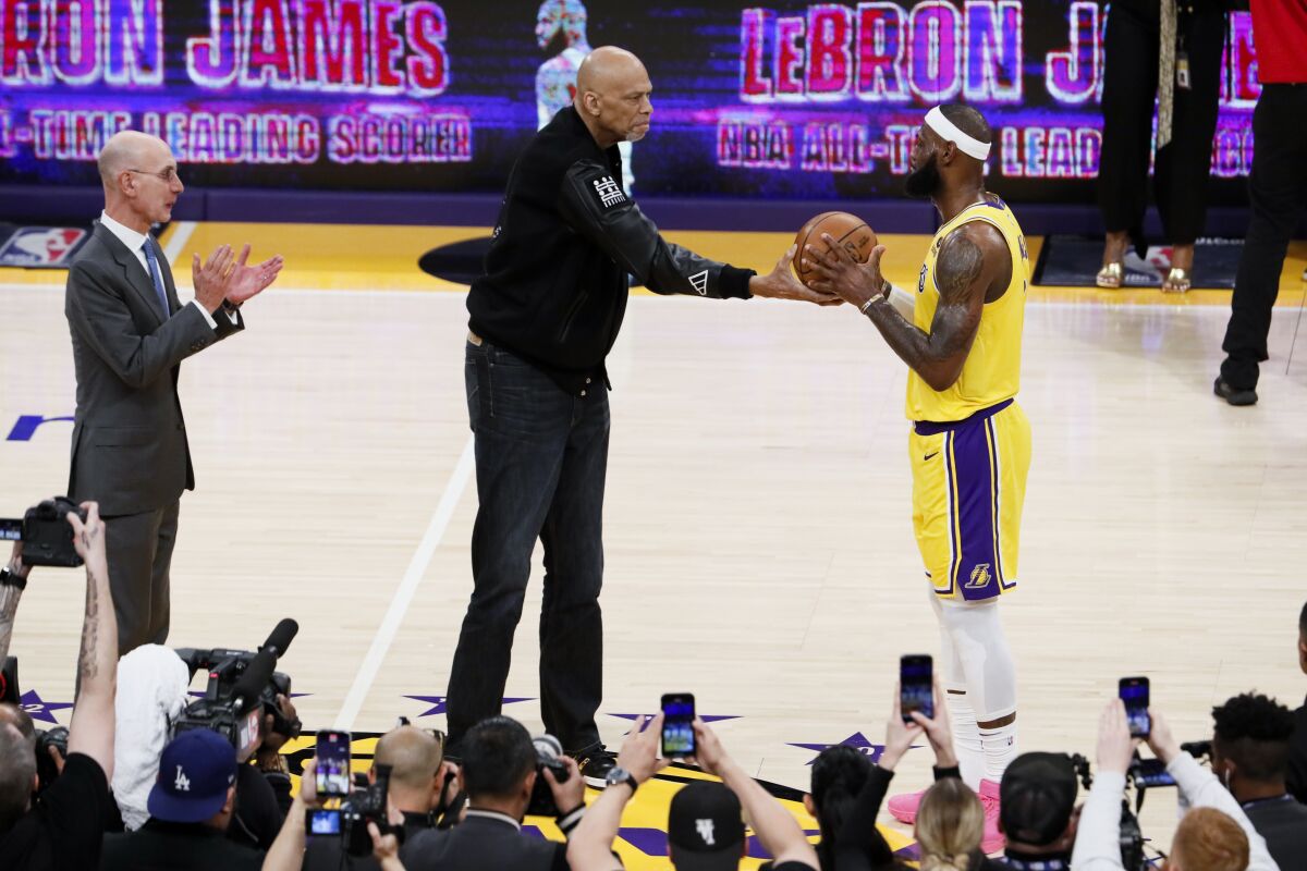 Kareem Abdul-Jabbar, left, passes a ball to LeBron James after James became the all-time NBA scoring leader on Feb. 7.