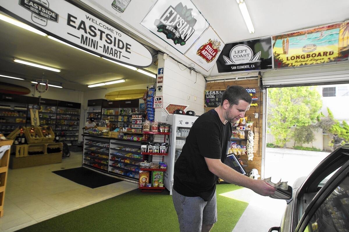 Colby Reedy assists a customer at Costa Mesa's Eastside Mini-Mart on Monday. The drive-through convenience store is at 1712 Santa Ana Ave.