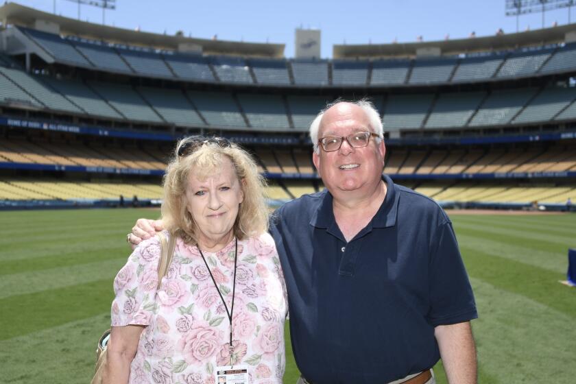 Dodgers official scorekeeper Dennis D'Agostino and his wife, Helene Elliott, stand together at Dodger Stadium.