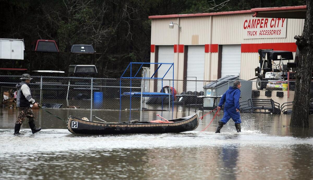 A pair of men pull a canoe past a flooded business along U.S. Highway 49 in Hattiesburg, Miss..