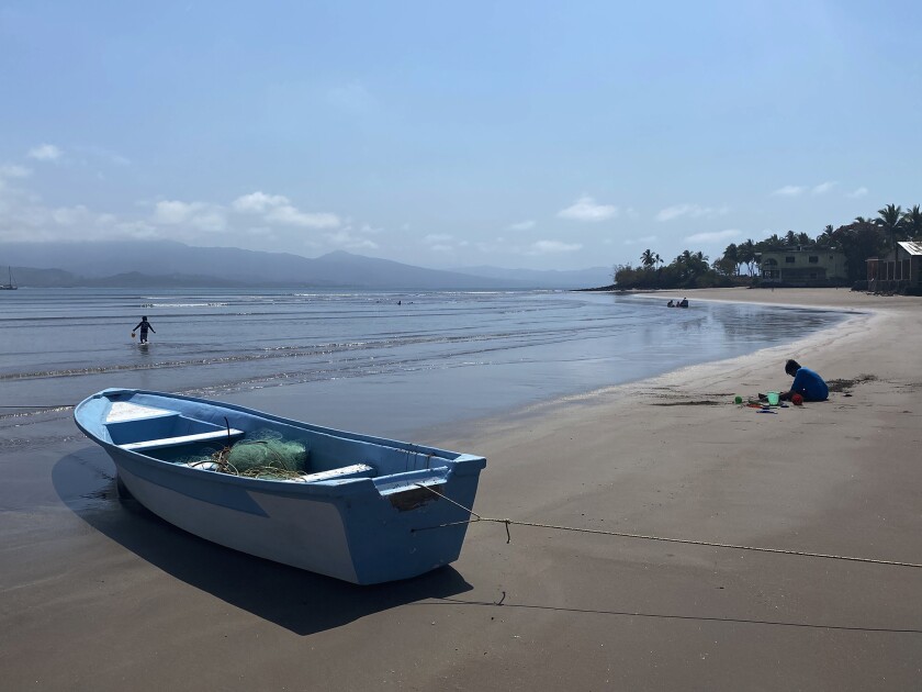 A beach in San Blas is still secluded with a fishing boat, a child playing in the sand and a swimmer.