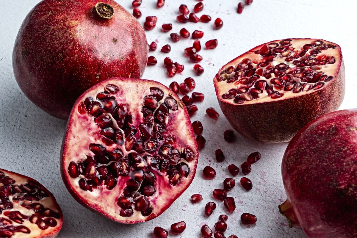 A pomegranate cut in half with seeds spilling out.