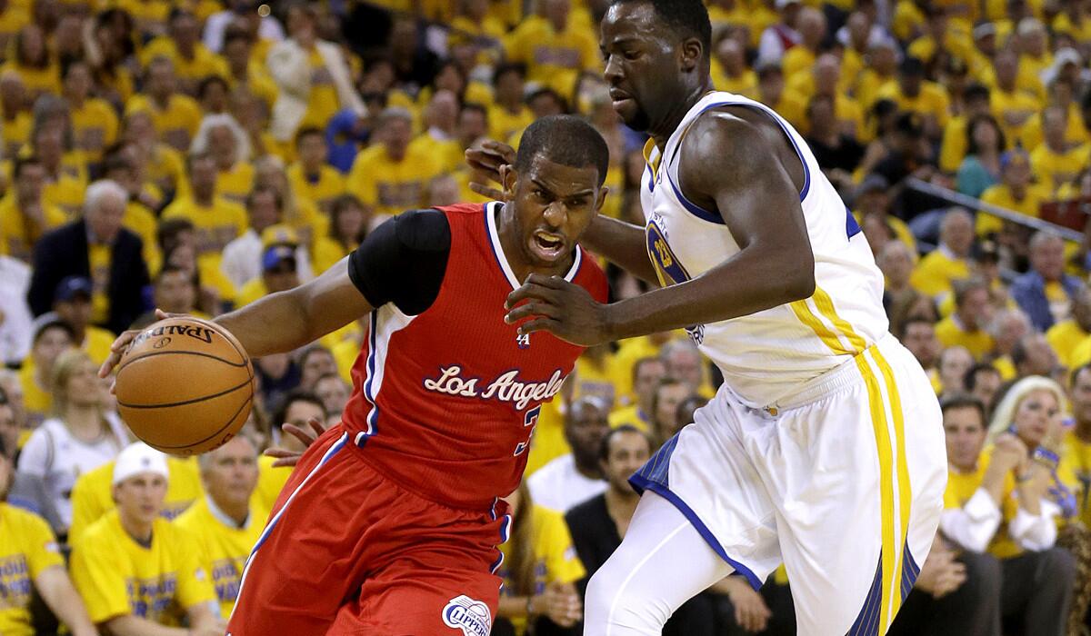 Clippers point guard Chris Paul, left, drives to the basket against Warriors forward Draymond Green in the first half.