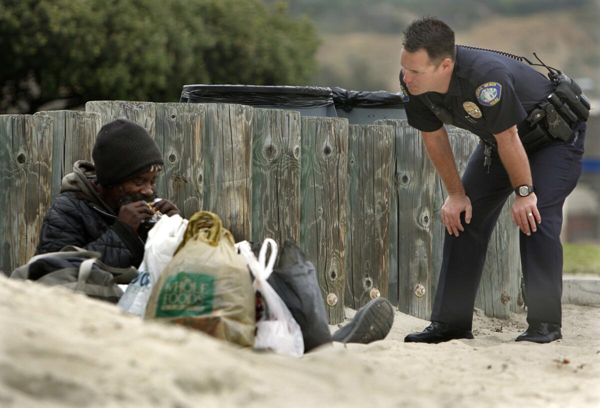 A Laguna Beach police officer speaks to a homeless man.