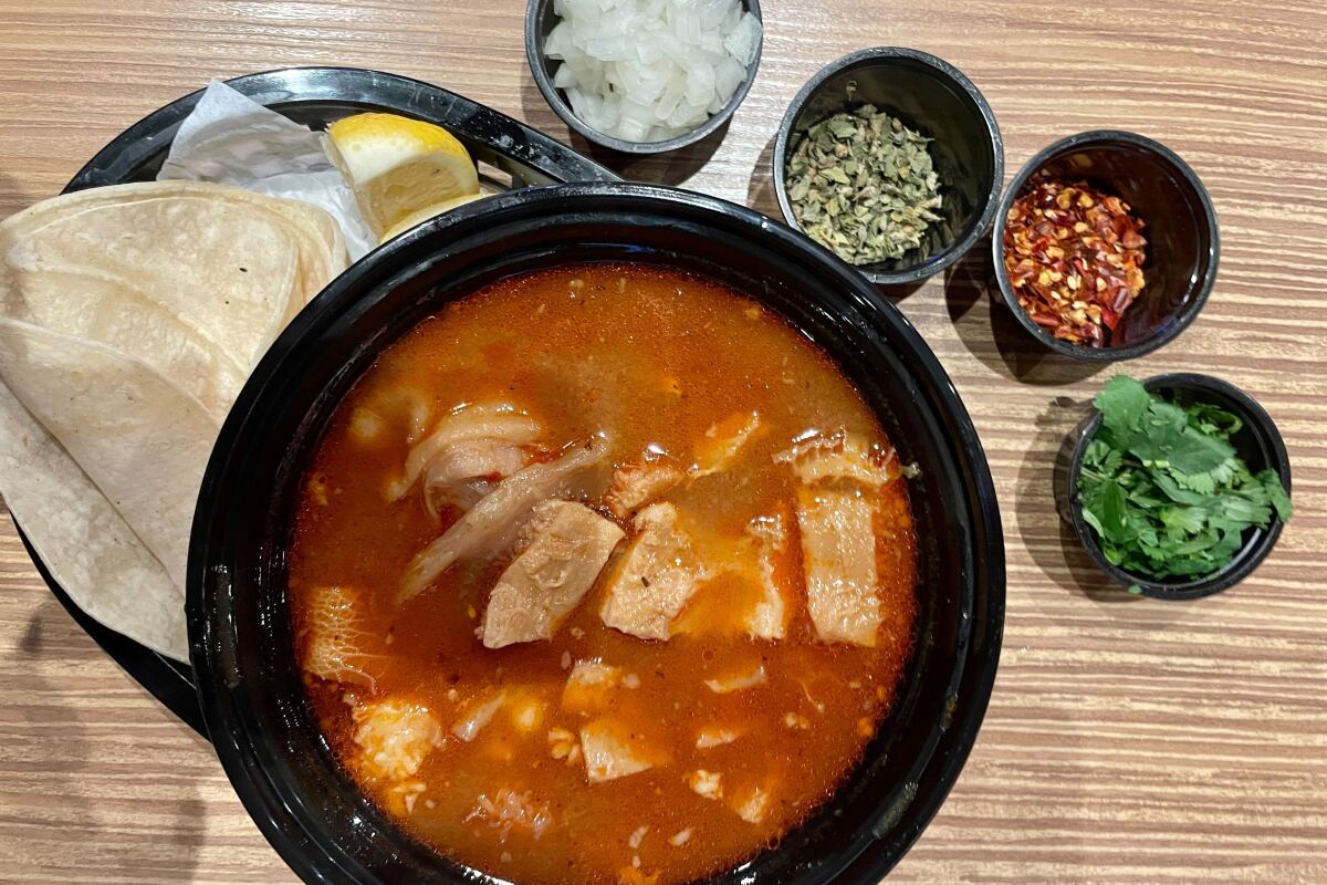 overhead view of soup in a bowl and four smaller bowls of toppings