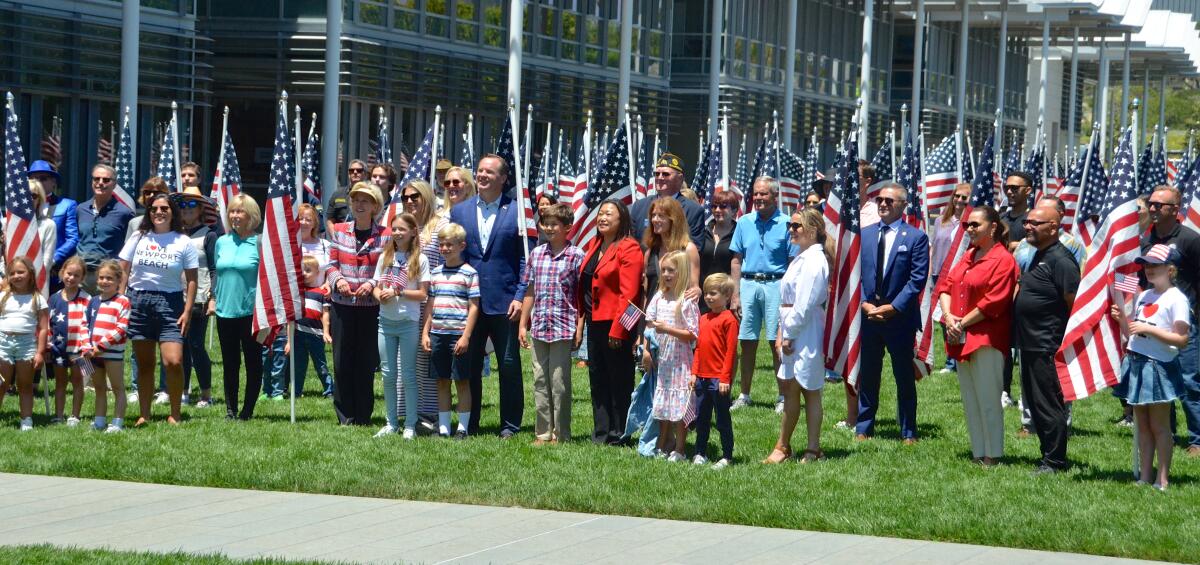 Numerous dignitaries with a multiple U.S. flags.