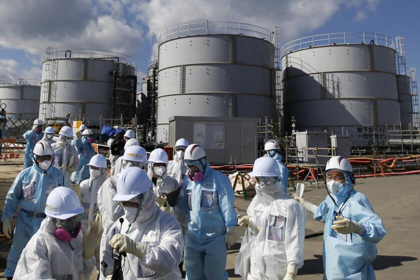 A media tour group in protective suits stands near the tsunami-crippled Fukushima Daiichi nuclear power plant in Okuma, Japan, on Feb. 10, 2016.