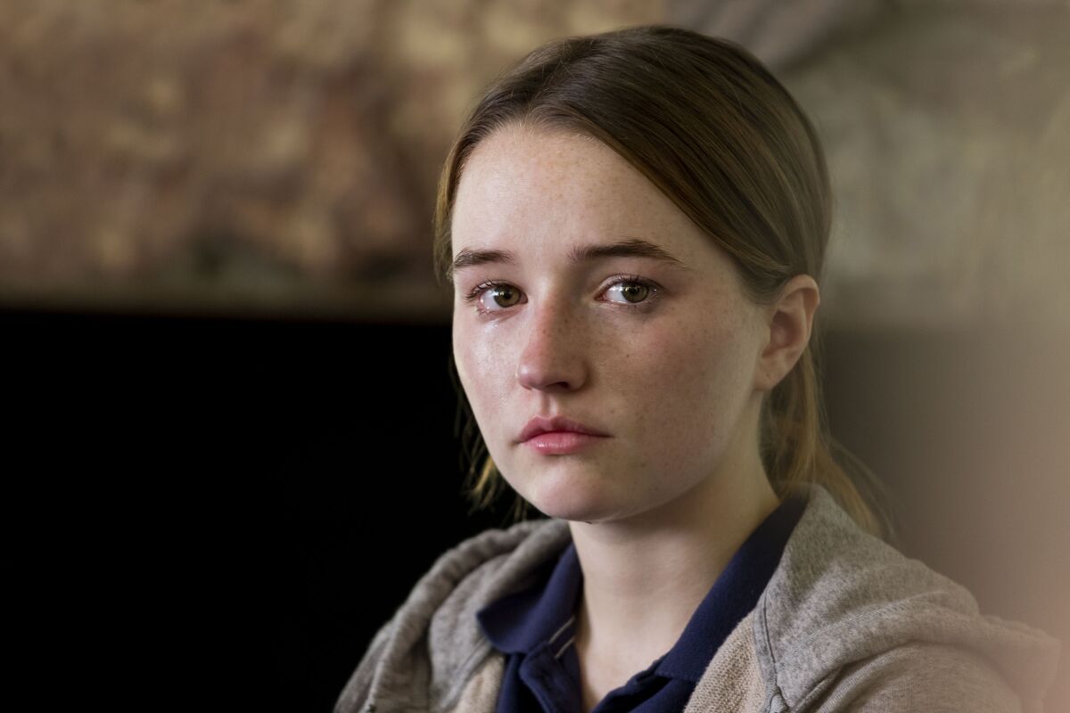 A woman cries while wearing a gray sweatshirt.