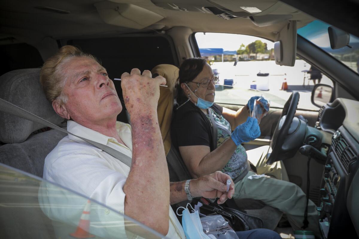 Daniel  and Linda Mendoza take COVID-19 tests at a drive-in site in Santa Ana.
