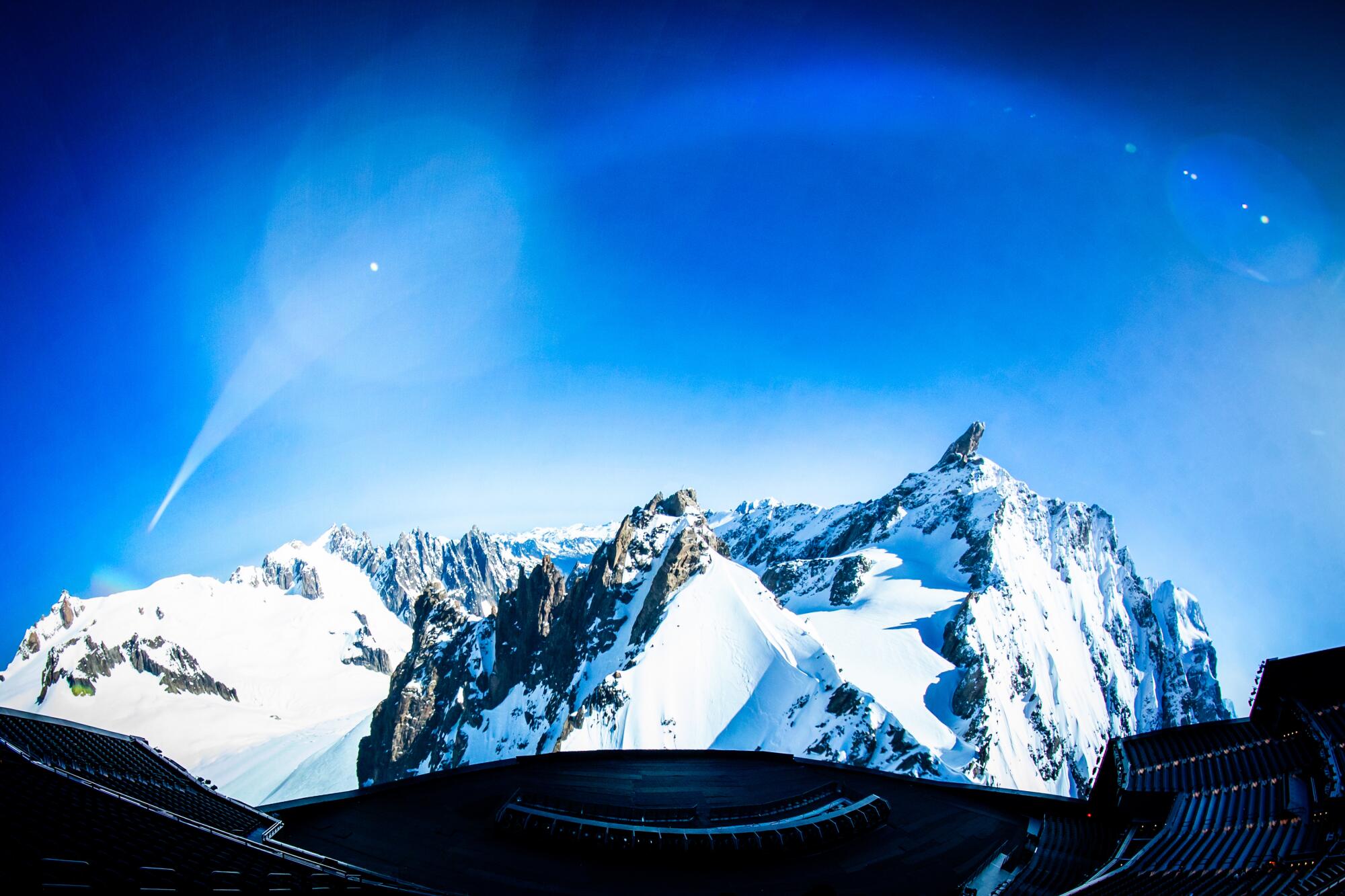 The snow capped tip of rocky mountains emerge are seen on a massive circular screen in an empty theater