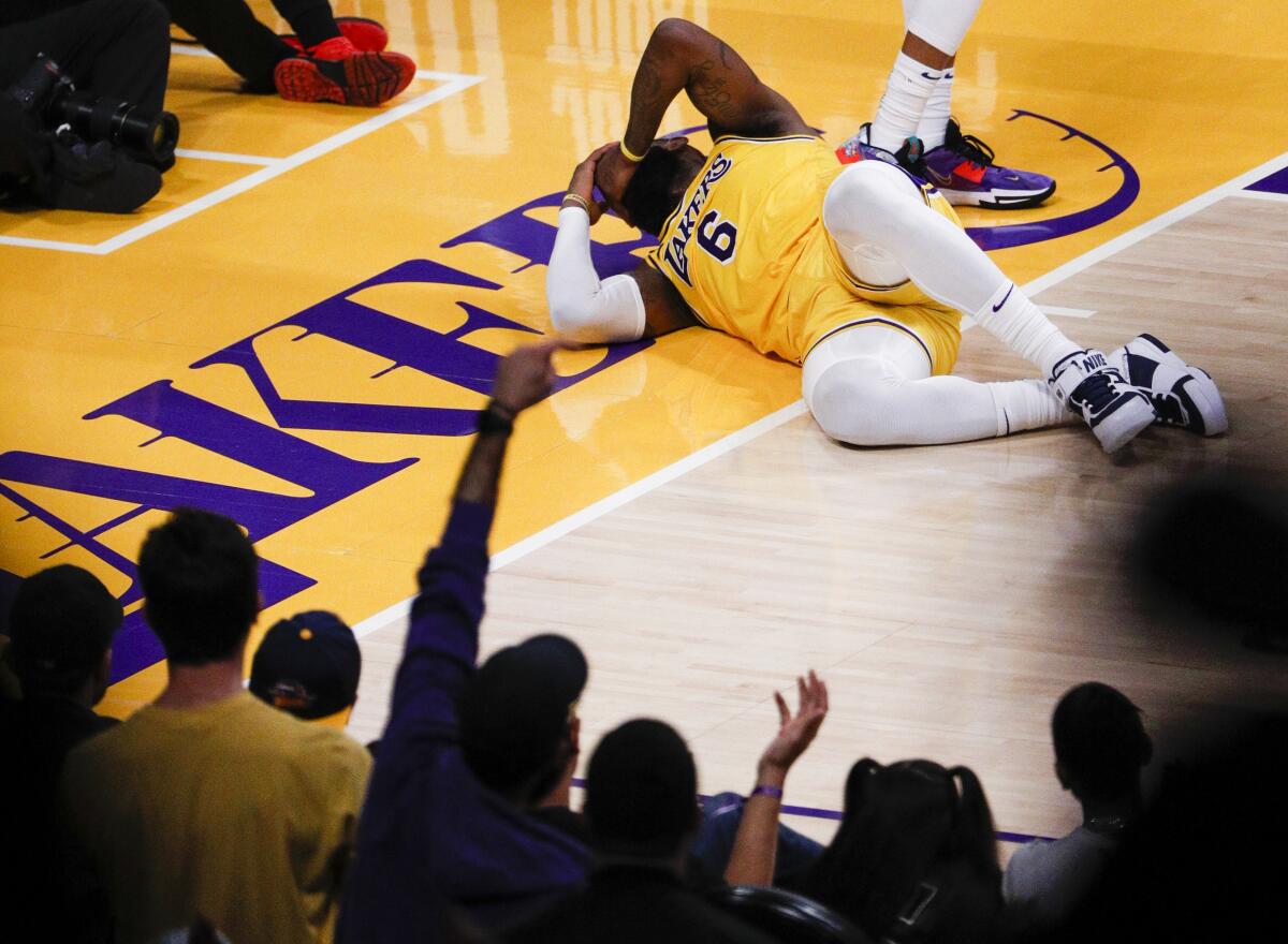 Lakers forward LeBron James lays on the court after being fouled by Warriors forward Andrew Wiggins while scoring on a layup.