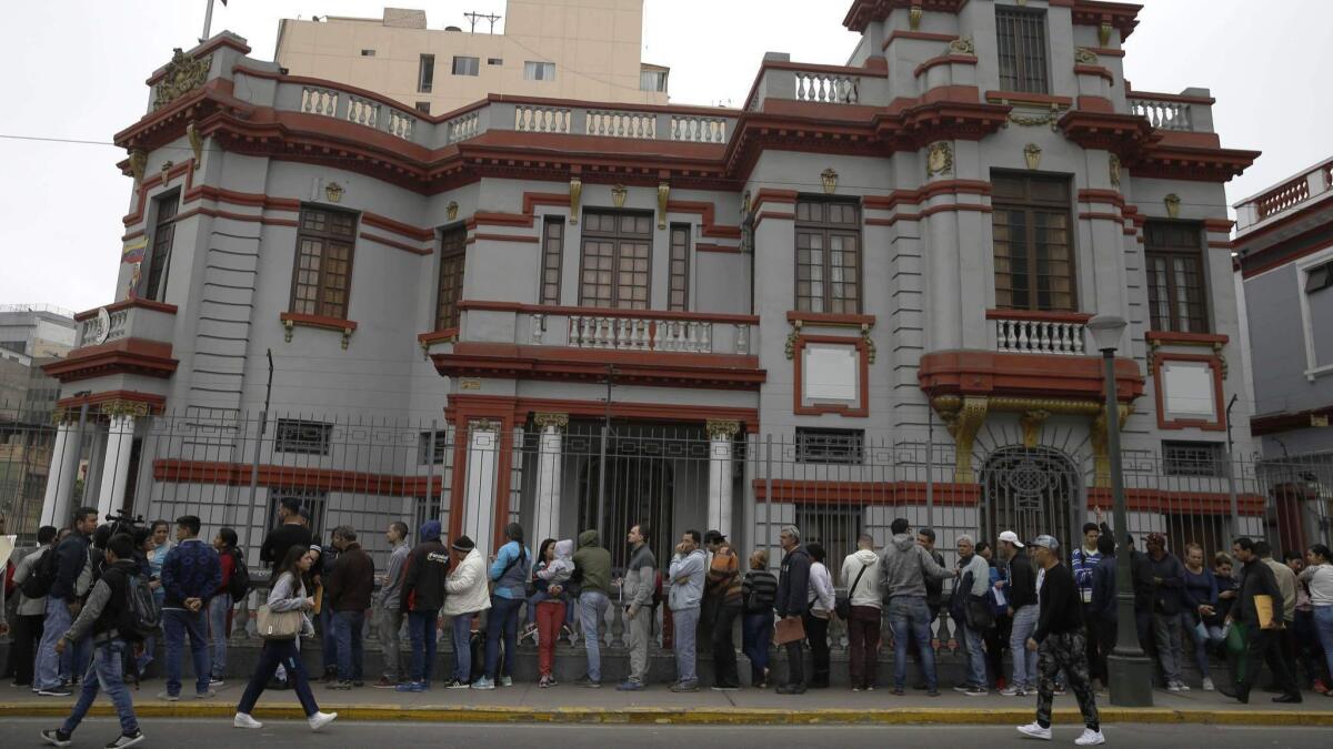 Venezuelans who recently moved to Peru wait outside the Venezuelan Embassy in Lima on Tuesday to try to get on a list for a government-financed flight home.