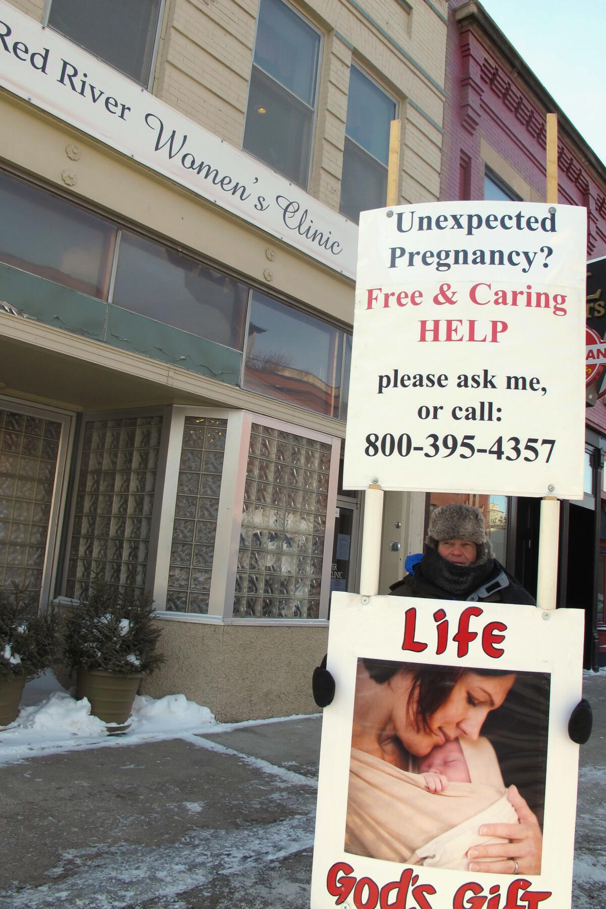 FILE - An abortion protester stands outside the Red River Valley Women's Clinic in Fargo, N.D., on Feb. 20, 2013. North Dakota's only abortion clinic, the Red River Women's Clinic, has gone to federal court seeking to declare the state's imminent abortion ban is contrary to the state constitution. (AP Photo/Dave Kolpack, File)
