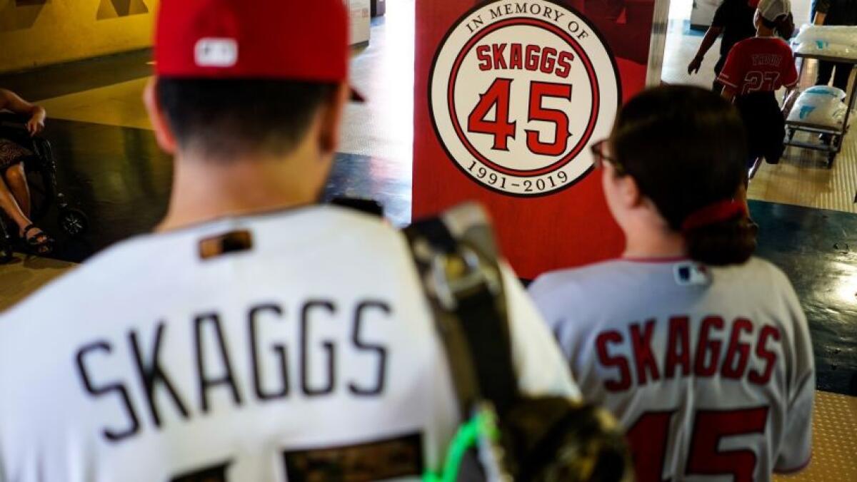 David Palacios, de 40 años, y su hija Emma, de 15, de Covina toman fotos de un marcador en memoria de Tyler Skaggs antes del inicio del juego de los Angels el viernes por la noche. (Kent Nishimura / Los Angeles Times)