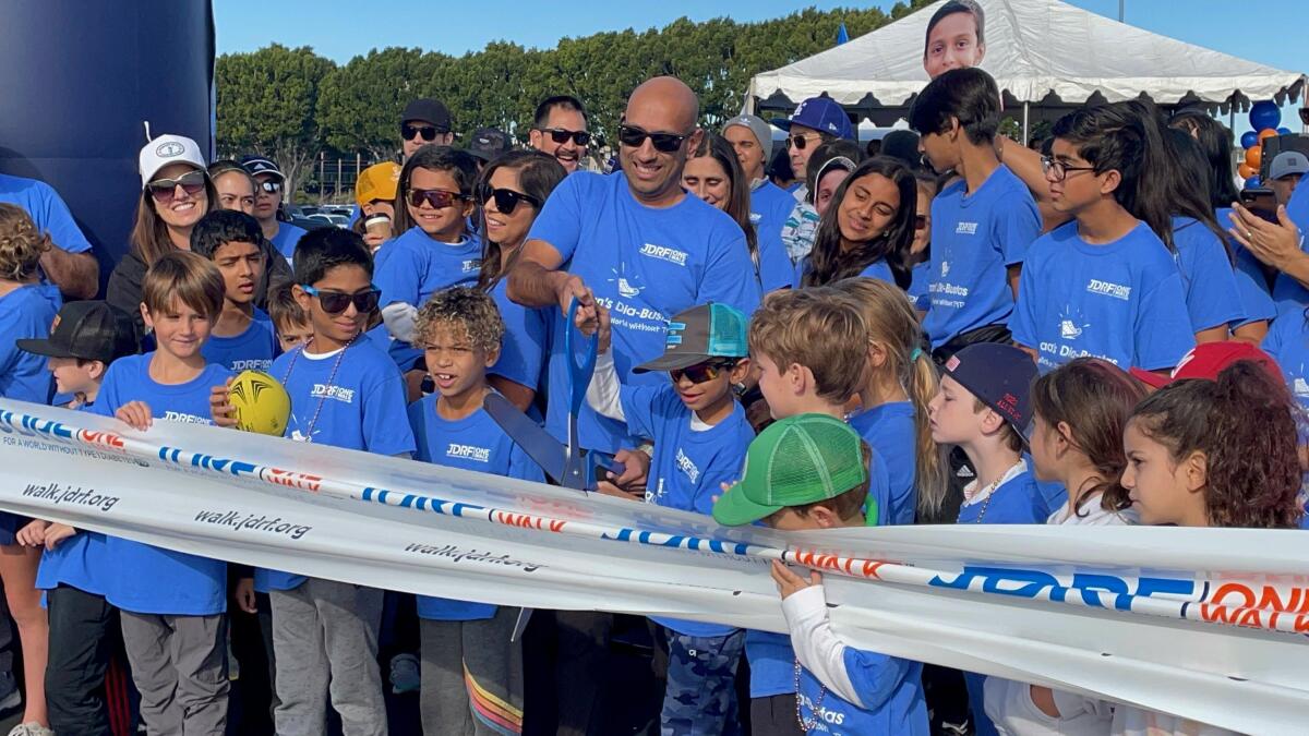 Vijay and Riaan Pai, center, cut the ribbon for the JDRF One Walk for the Orange County chapter in 2022 at Angels Stadium.