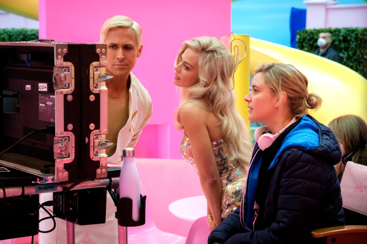 Ryan Gosling, Margot Robbie and Greta Gerwig check a monitor on the set of "Barbie." 