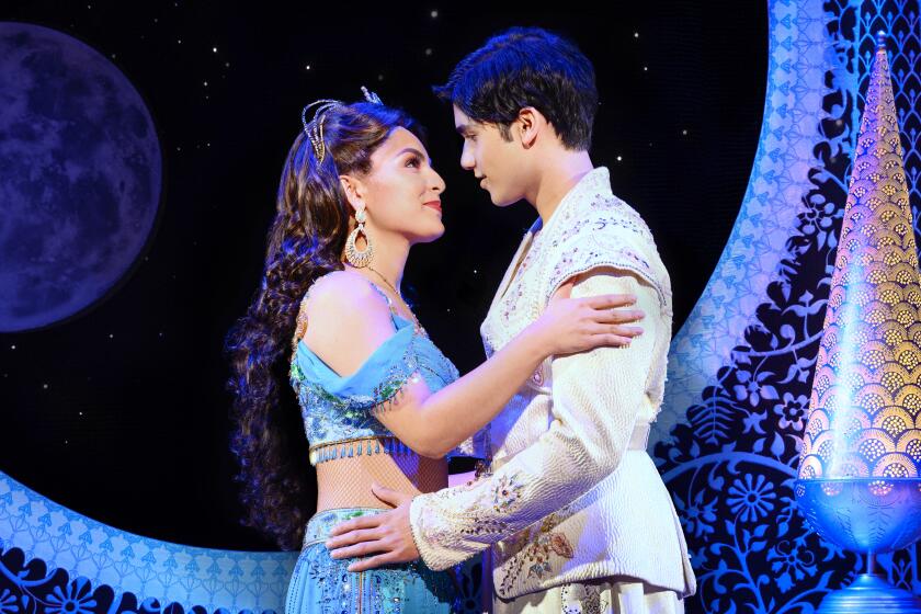 Actors playing Jasmine and Aladdin in the musical "Aladdin" embrace.