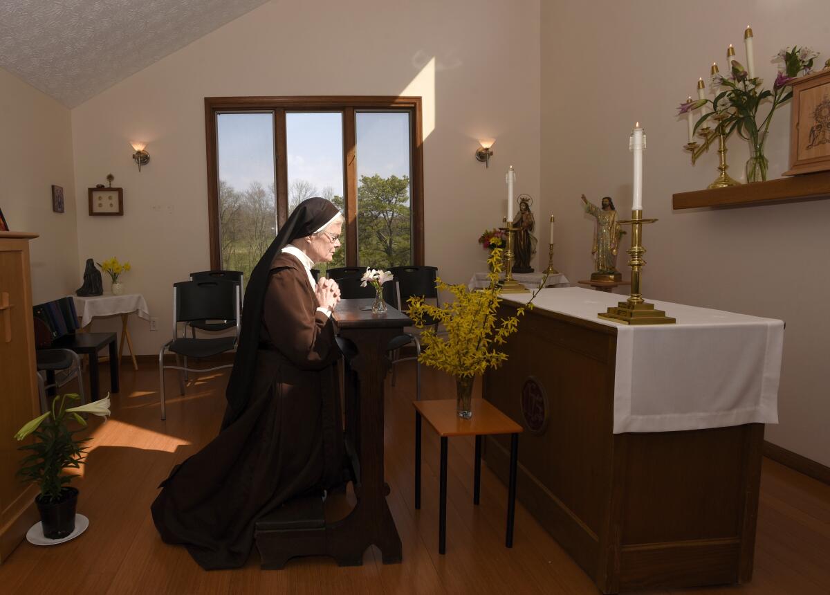 The Rev. Sister Barbara Smith, of the Order of Discalced Carmelites, prays on a prayer bench that belonged to The Rev. Mychal Judge, the Fire Department of New York's chaplain who died in the 2001 attacks on the World Trade Center, at the Episcopal Carmel of Saint Teresa in Rising Sun, Md., on Sunday, April 4, 2021. The Episcopal Carmel of Saint Teresa donated the prayer bench to the National Sept. 11 Memorial and Museum, representatives of which acquired the bench later in the morning. (AP Photo/Steve Ruark)