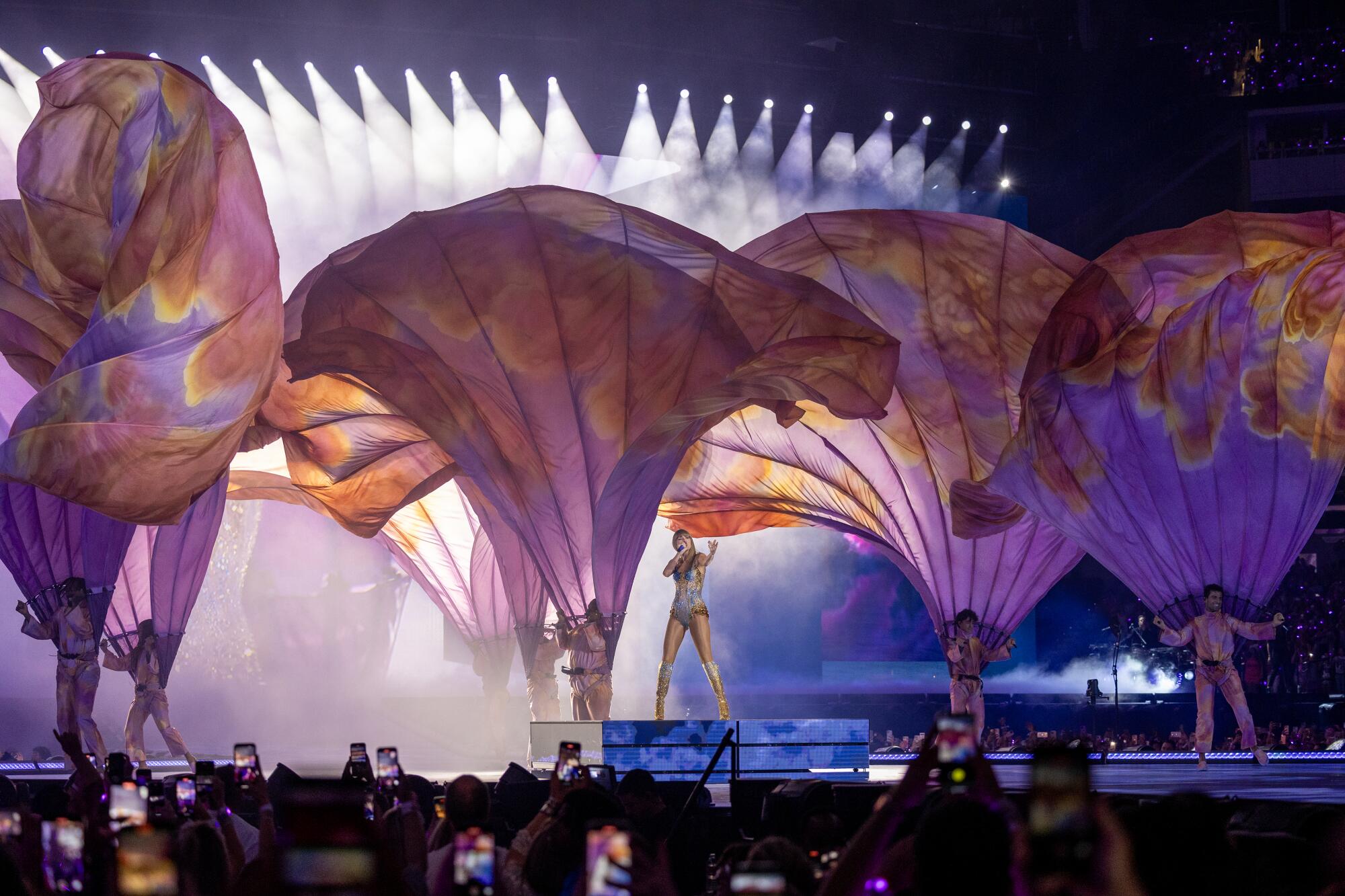 Taylor Swift performs while other performers hold billowing material.