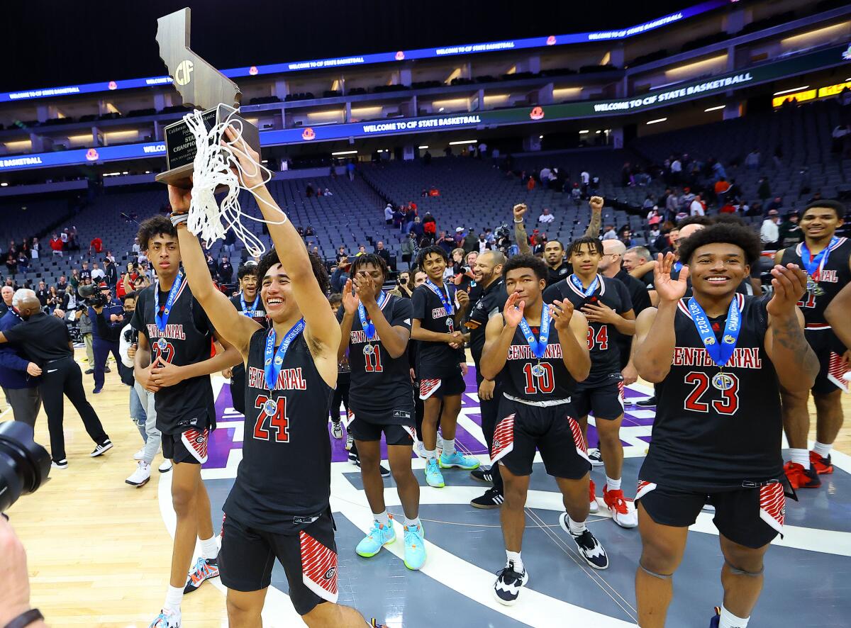 Jared McCain of Corona Centennial High hoists the state championship trophy with a net draped over it.