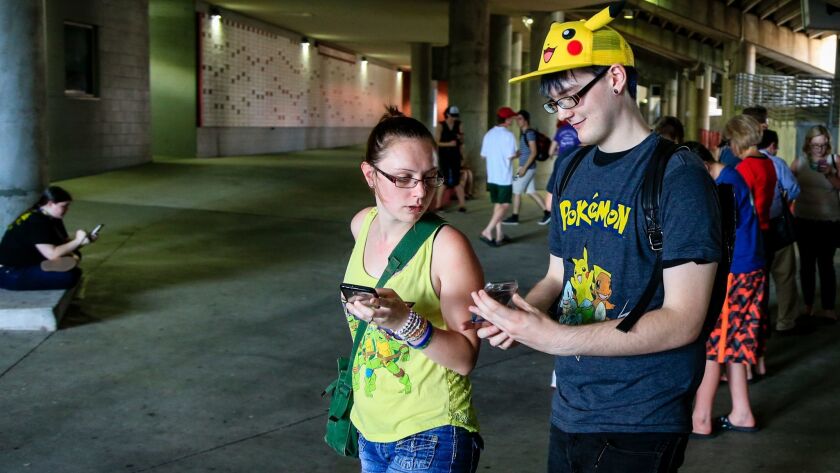 Pokemon Go players consult each other while catching digital monsters at Memorial Stadium in Lincoln, Neb. Even though the game forces players to walk around, it's not enough to count as a workout, a new study finds.