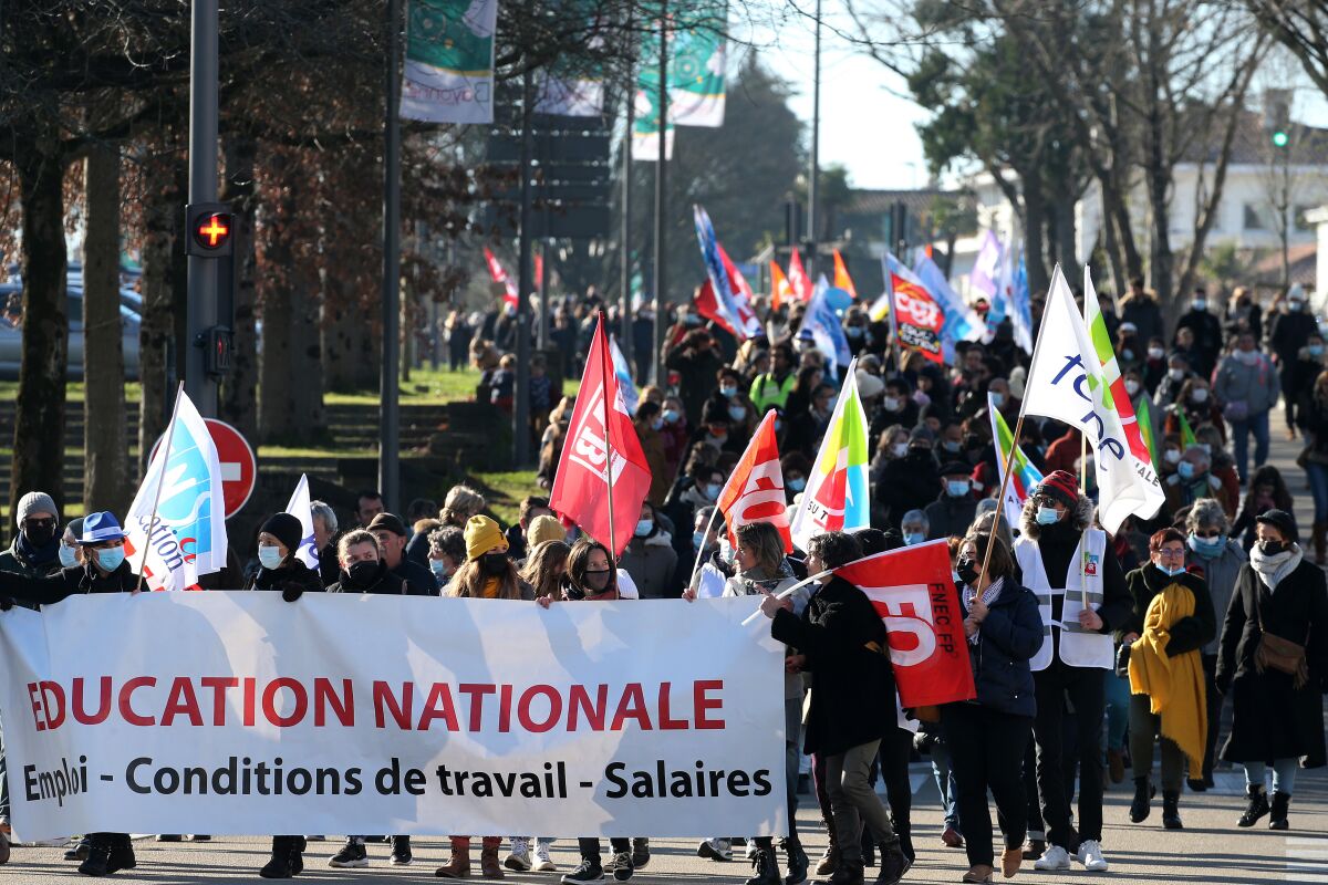 Teachers and students hold a banner reading " National Education- working condition - wages " as they demonstrate in Bayonne, southwestern France, Thursday, Jan. 13, 2022. French teachers have walked out in a nationwide strike Thursday to express anger at the way the government is handling the virus situation in schools, denouncing confusing rules and calling for more protection. (AP Photo/Bob Edme)