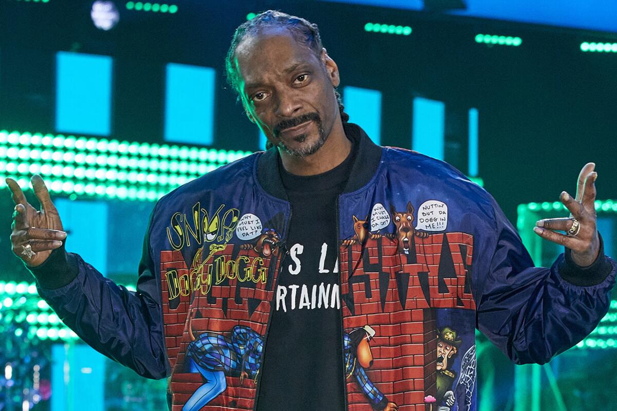 Snoop Dogg wears a red and blue jacket with his name on it.