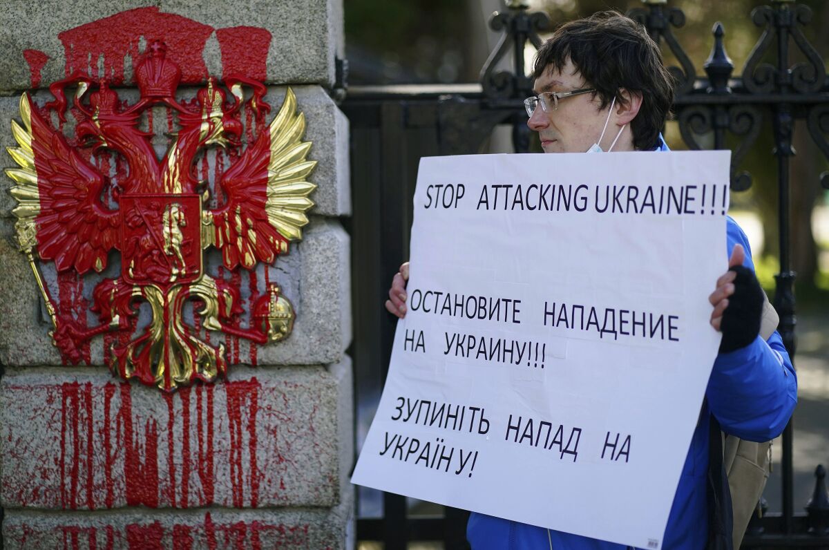 A Ukrainian living in Ireland protests at the Russian Embassy gate in Dublin, where red paint was poured on the coat of arms.