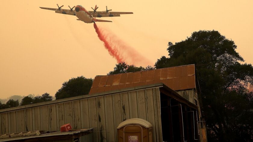 A firefighting air tanker drops fire retardant near a structure ahead of the County fire, which authorities say was caused by an improperly installed electric livestock fence. The blaze has scorched 90,000 acres in Yolo and Napa counties.
