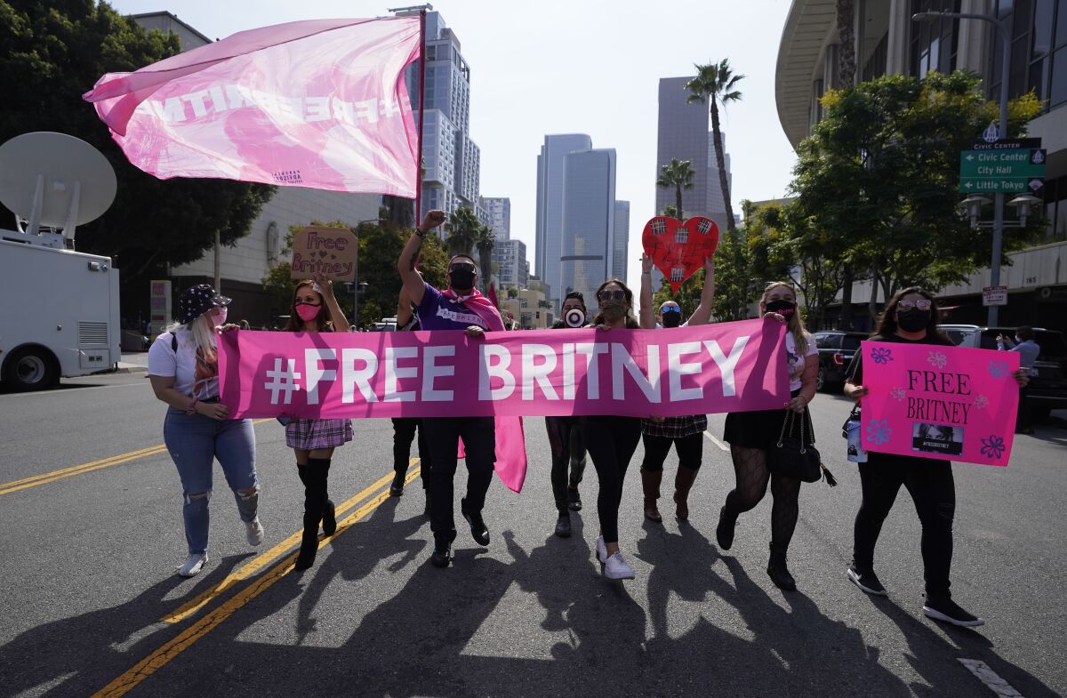 Britney Spears supporters carry a banner down a street