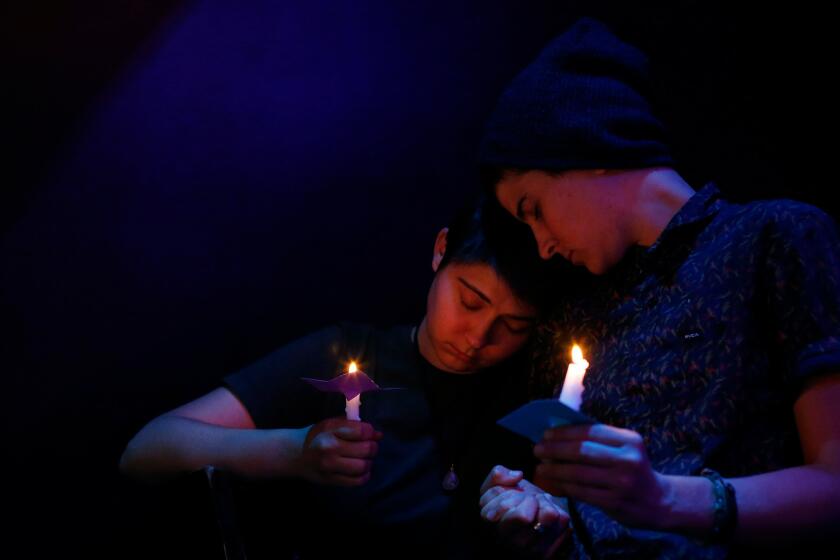 Sisters Sarah Bryant, left, and Katy Bryant, both from Irvine, listen as the names of the Orlando shooting victims are read during a vigil at the Velvet Lounge, a gay bar and club in Santa Ana. The event was an OC Faith-Leader Collective gathering.