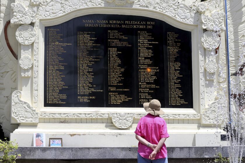 A foreign tourist looks at the plaque bearing names of the victims of the Bali bombings at the Bali Bombing Memorial Monument in Kuta, Bali, Indonesia on Thursday, Dec. 8, 2022. An Islamic militant convicted of making the explosives used in the 2002 attack that killed over 200 people was paroled Wednesday, after serving about half of his original 20-year prison sentence, despite strong objections by Australia, which lost scores of citizens in the Indonesian attacks. (AP Photo/Firdia Lisnawati)