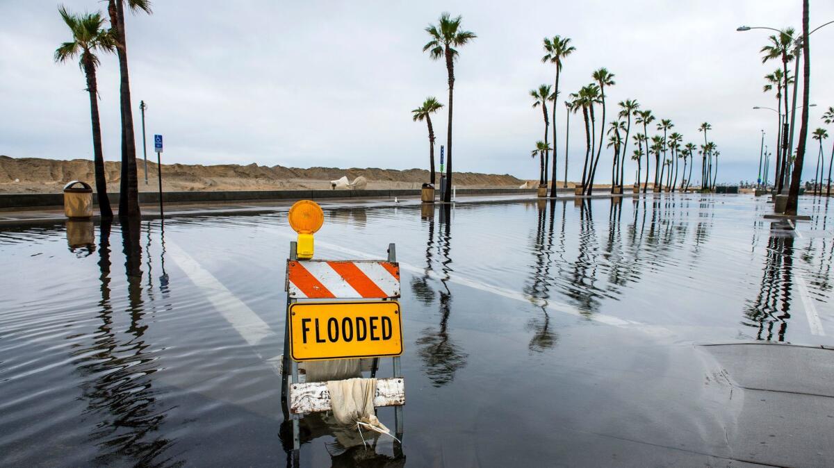 A sign lets visitors know that a beach parking lot near the Balboa Pier in Newport Beach is flooded on Feb. 18.