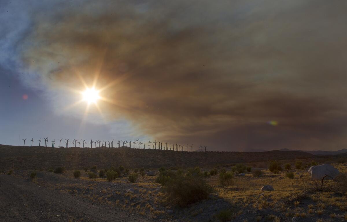 Wind turbines near the 10 freeway in Cabazon are framed by the smoke from the Lake fire