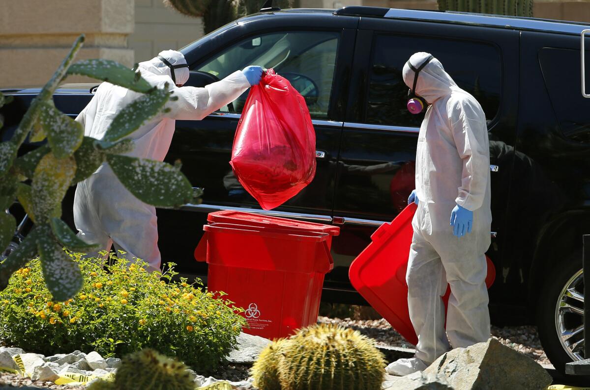 Workers remove items from the north Phoenix home where five family members were found shot to death Thursday. A man who had been in a business dispute with his two brothers shot and killed them, his mother and a sister-in-law before taking his own life, police said.