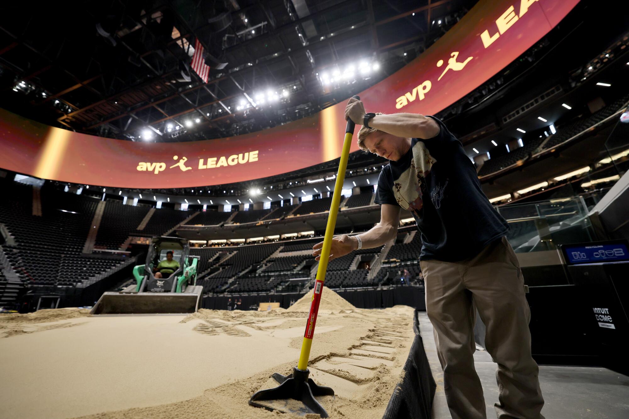 A worker prepares sand at the Intuit Dome ahead of an AVP tournament.