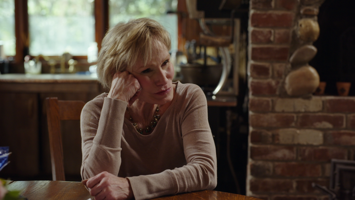 A woman sits in thought at her kitchen table while being filmed for a docuseries