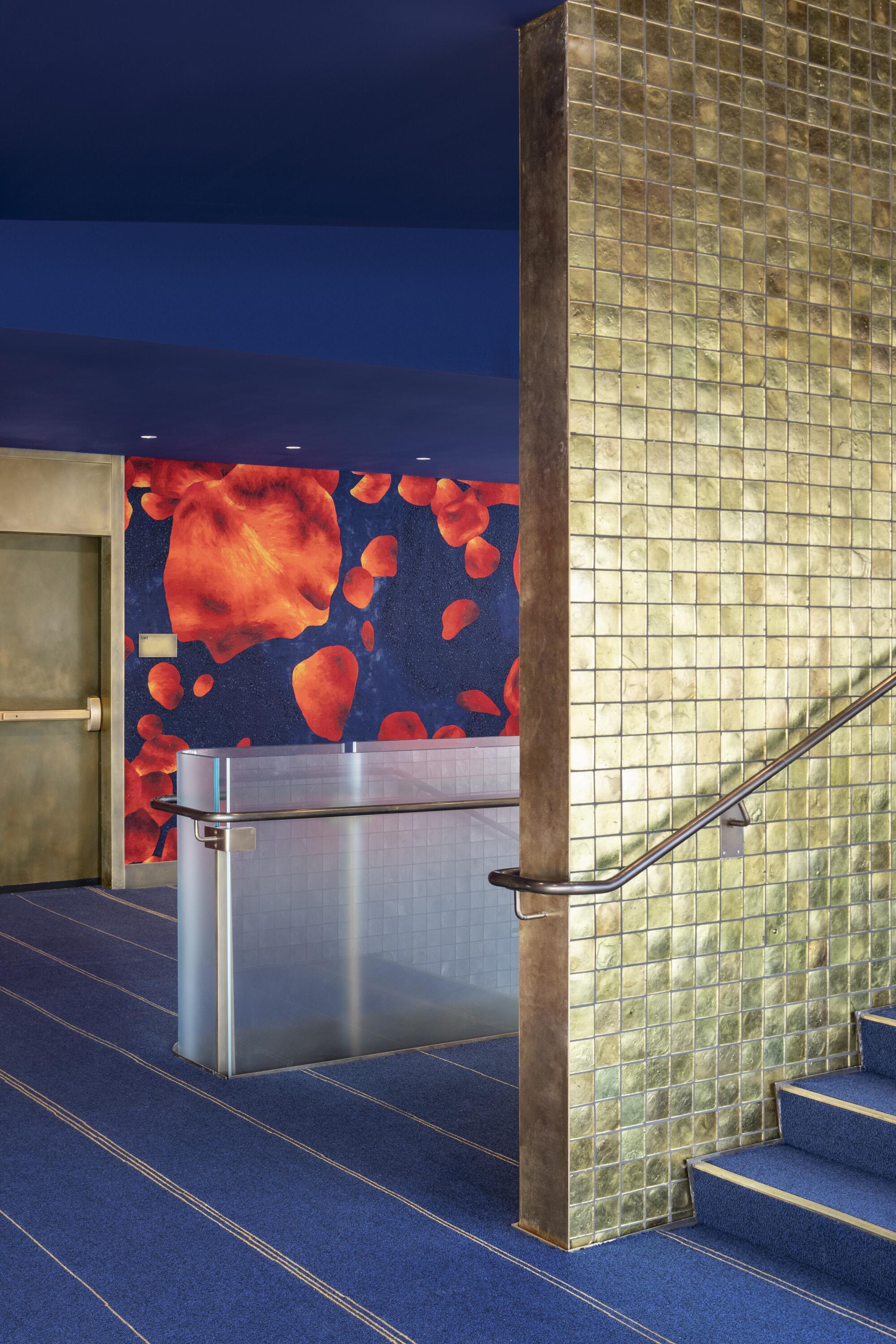 A stair descends along a wall clad in shimmering, gold tile. At rear, a wall features a pattern of falling rose petals.