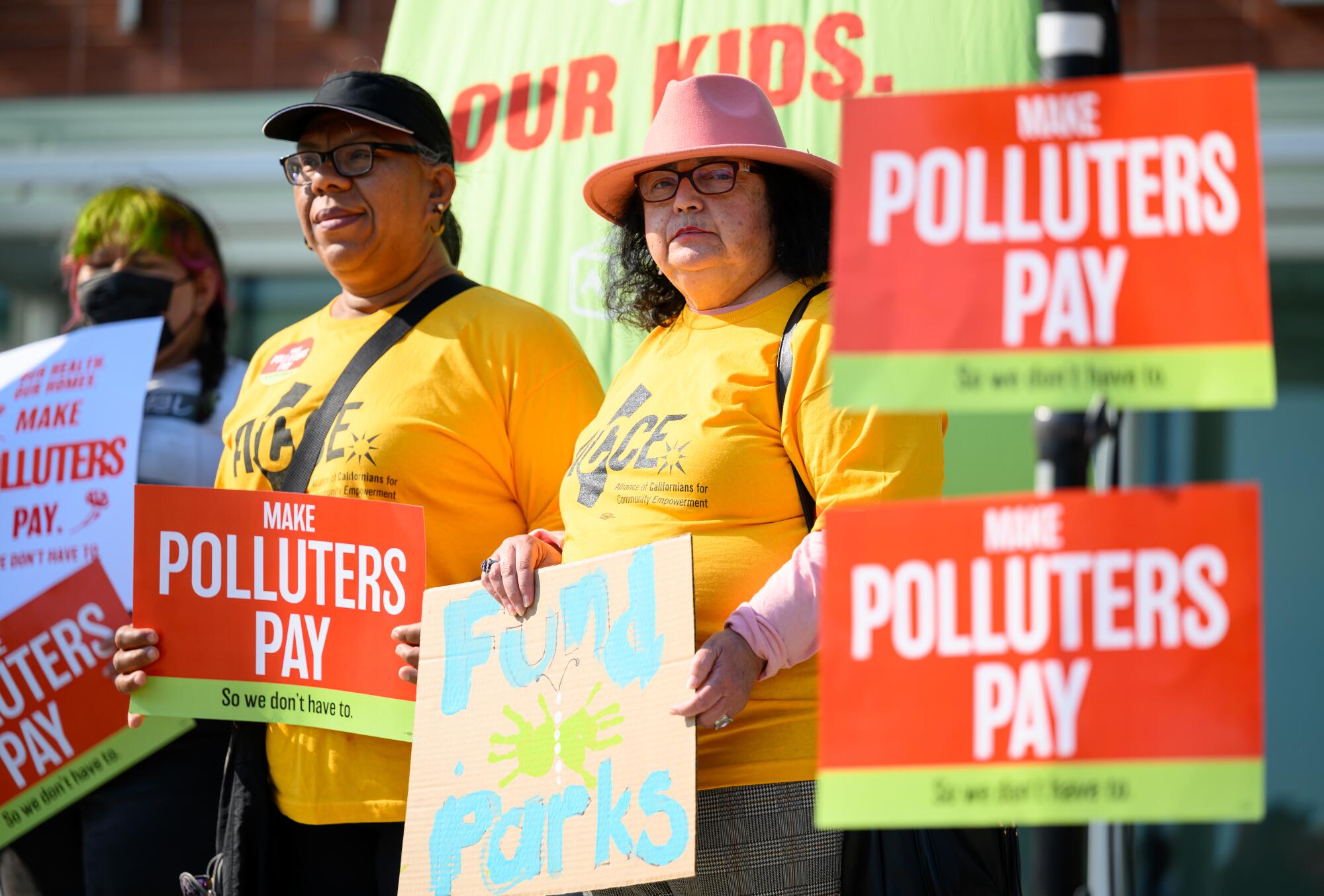 People hold signs that say "Make polluters pay."