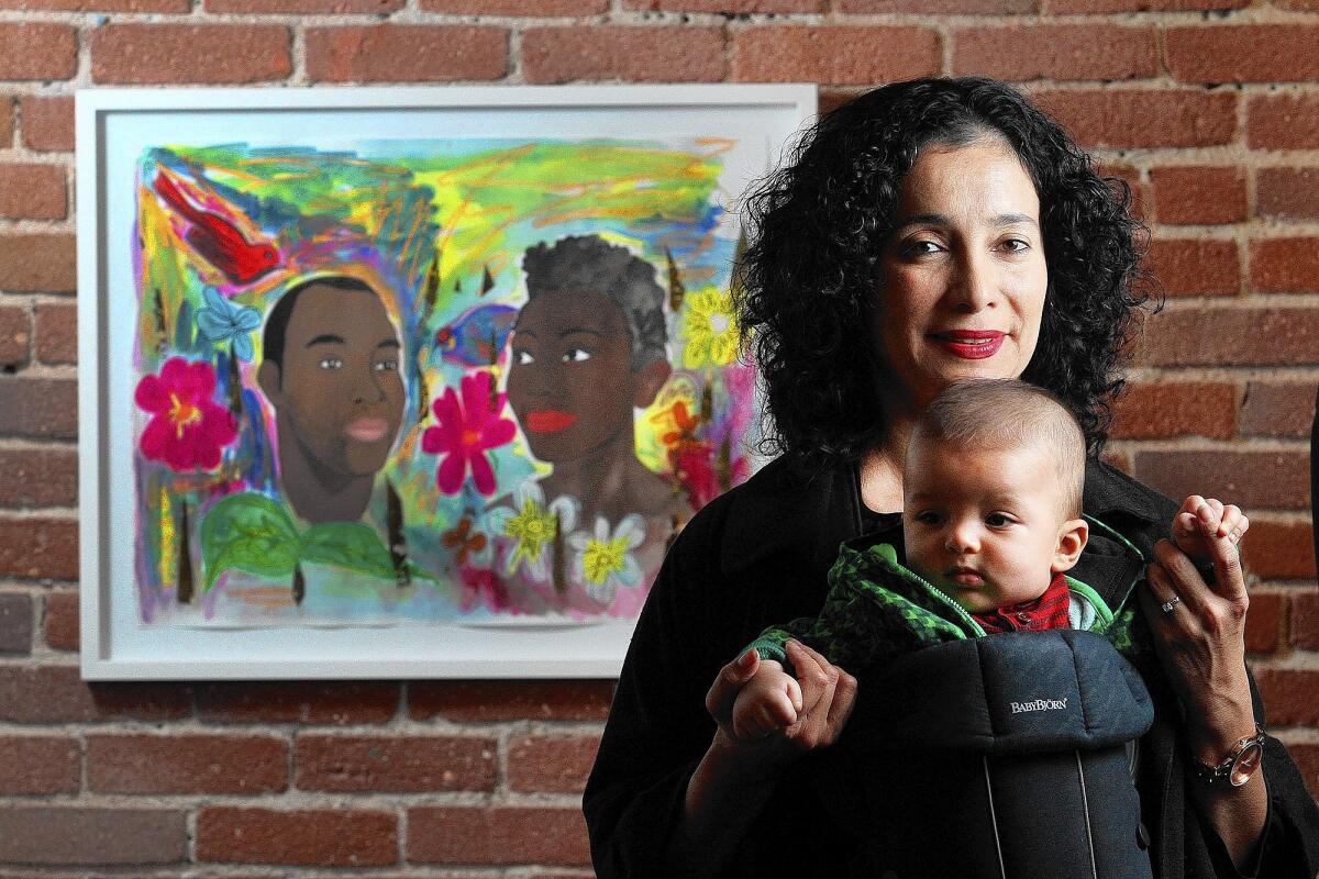 Carolyn Castaño, of Glendale, with her 5-month-old baby Toussaint, at a Black Panther exhibit including her 2014 painting "We Built This Garden" at Art Share L.A. in Los Angeles on Wednesday, Feb. 19, 2014. Castaño is one of 39 artists on display, including an mixed media piece by street artist Shepard Fairey.