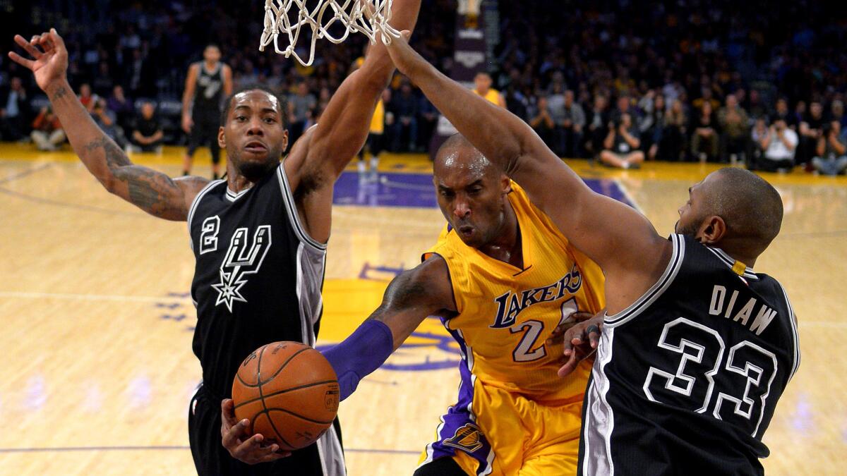 Lakers forward Kobe Bryant looks to pass after driving to the basket against Spurs forwards Kawhi Leonard, left, and Boris Diaw during a Jan. 22 game at Staples Center.