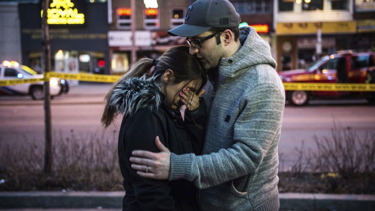 Farzad Salehi consoles his wife, Mehrsa Marjani, who was at a nearby cafe and witnessed the aftermath of a van plowing into pedestrians along a crowded Toronto sidewalk on Monday.