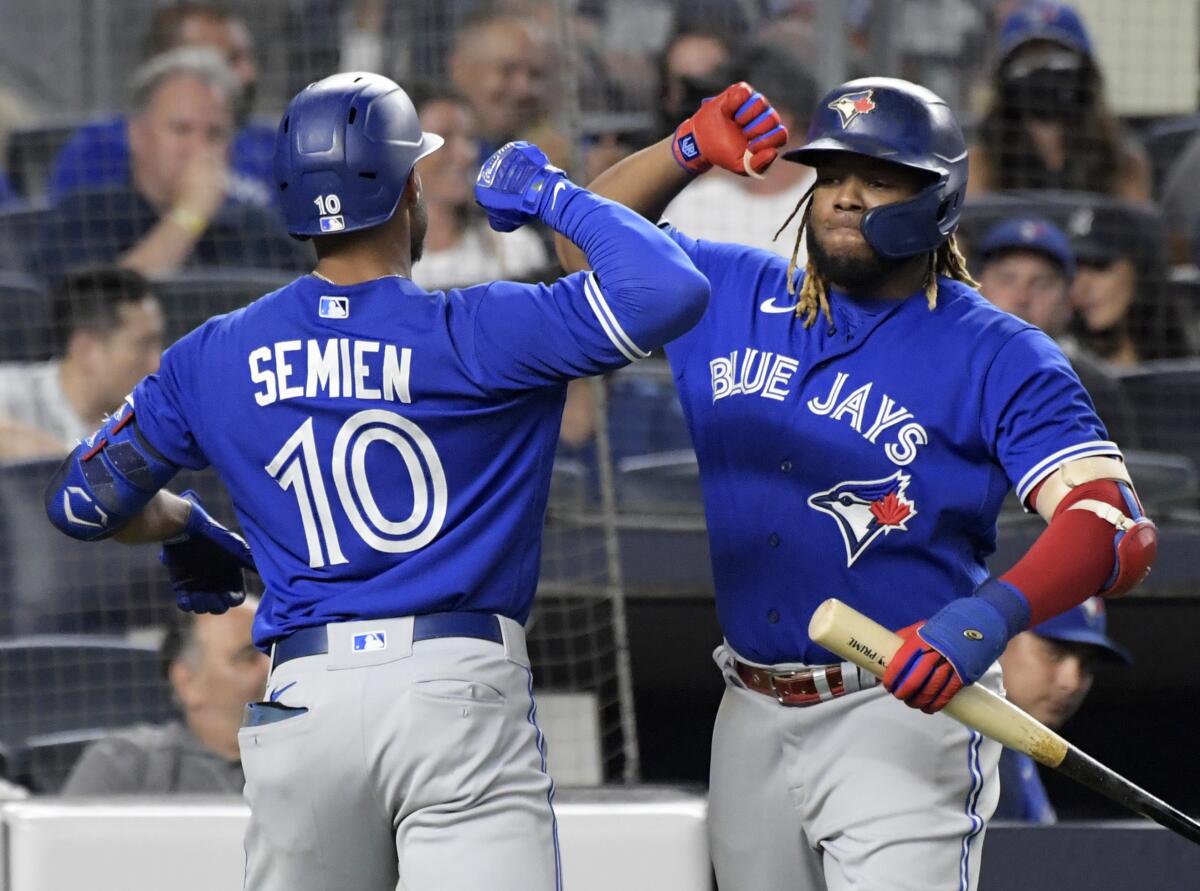 Toronto Blue Jays' Marcus Semien (10) celebrates with Vladimir Guerrero Jr. after Semien hit a home run against the New York Yankees during the fifth inning of a baseball game Tuesday, Sept. 7, 2021, at Yankee Stadium in New York. (AP Photo/Bill Kostroun)