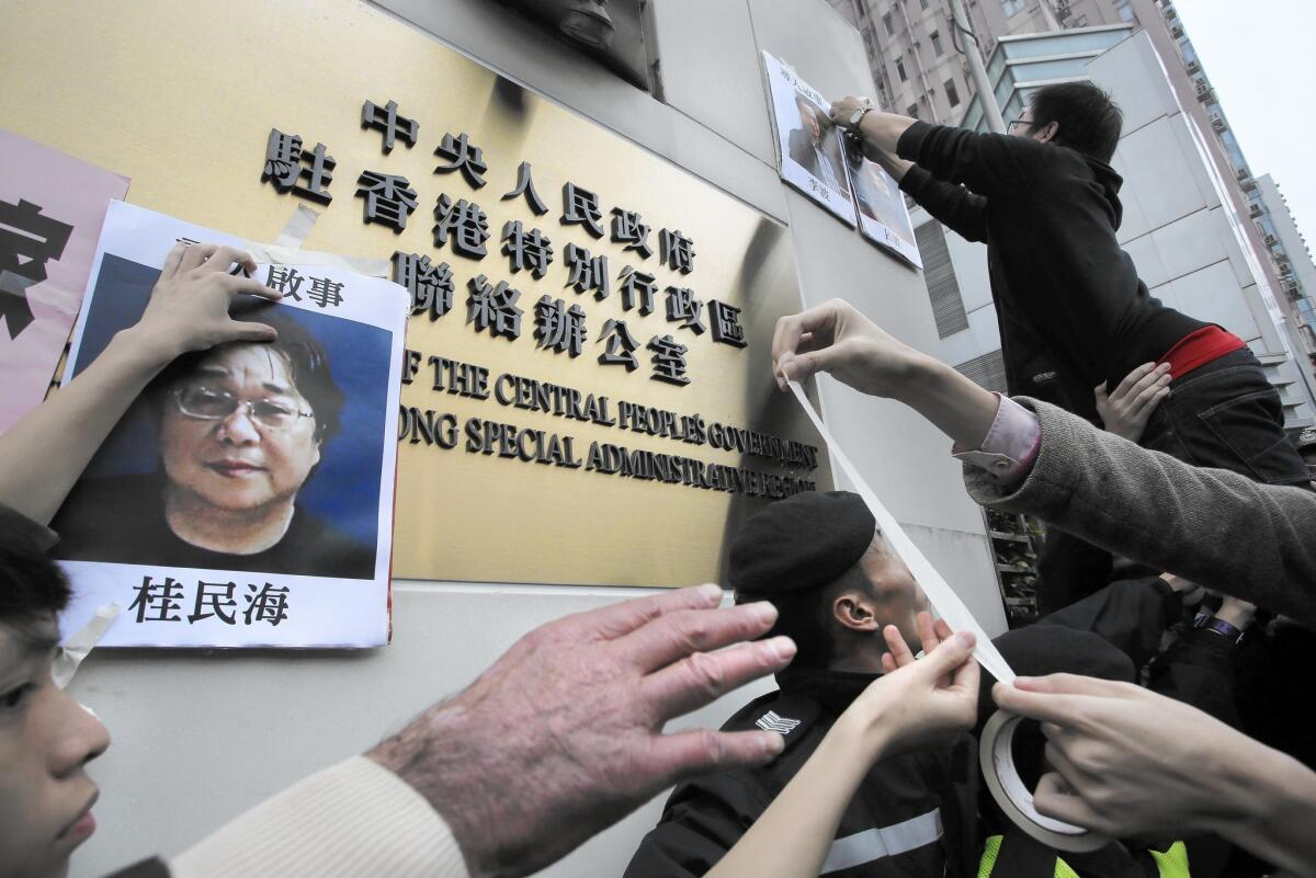 Protesters in January try to put up photos of missing booksellers, including Gui Minhai, left, during a protest outside the Liaison of the Central People's Government in Hong Kong.