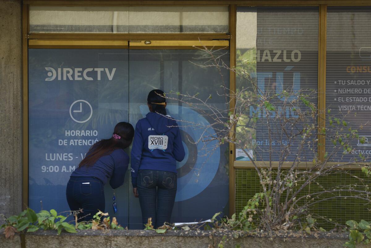 Customers wait to enter the DirecTV headquarters in Caracas, Venezuela.